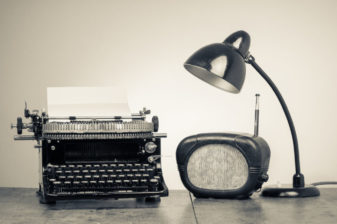 Vintage old type writer, radio and retro desk lamp on wood table